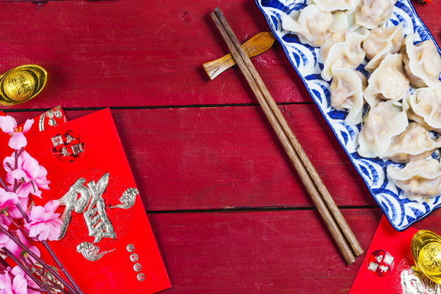 Chinese Jiaozi new year food, spring festival food on traditional spring festival Spring festival atmosphere and dumplings, ang pow or red packet and gold ingots. Chinese characters means luck,wealth